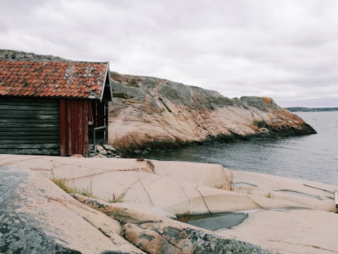 Ett rött timmerbodhus på klipporna vid den svenska kusten